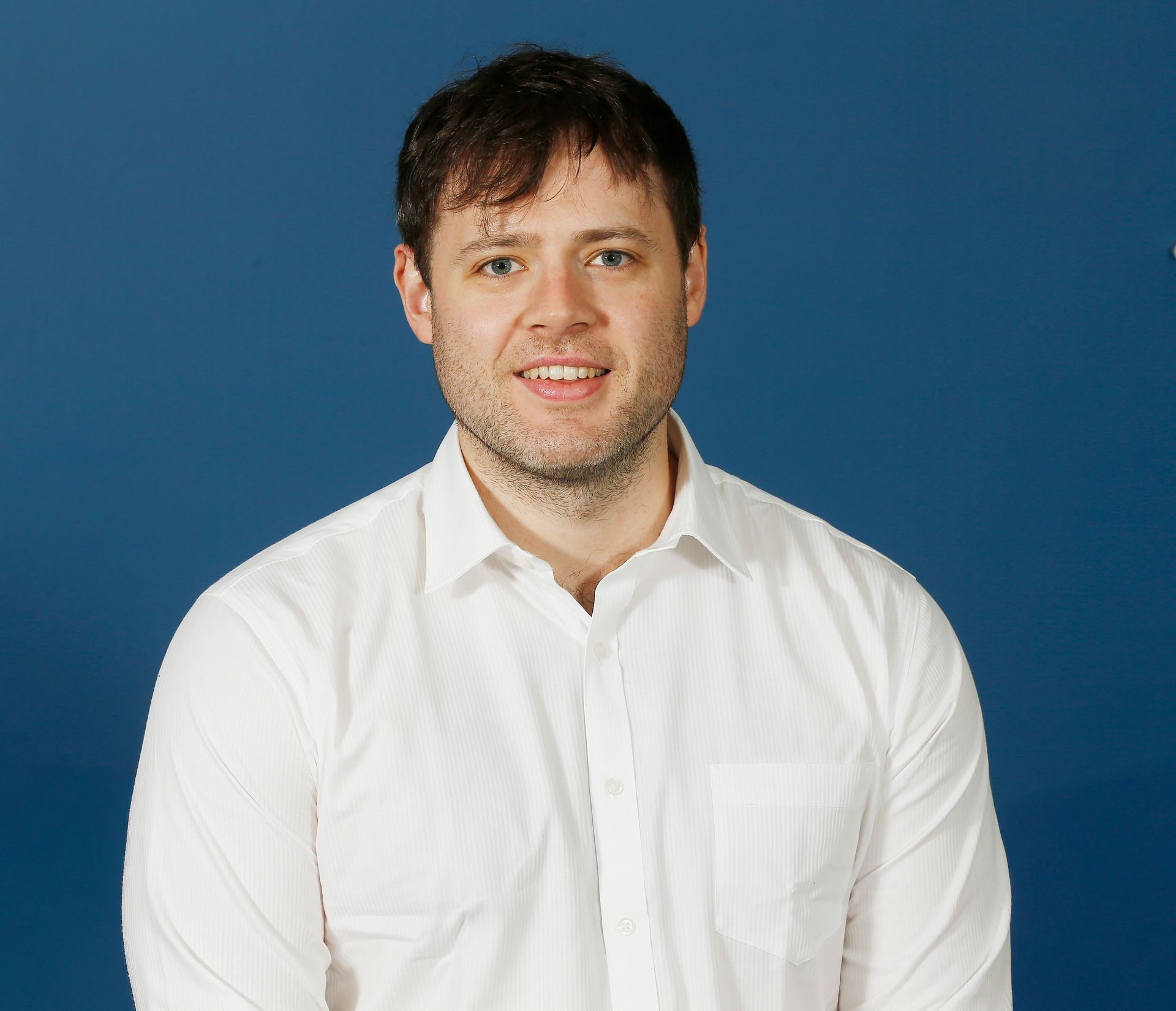 Person in a white shirt standing against a blue background
