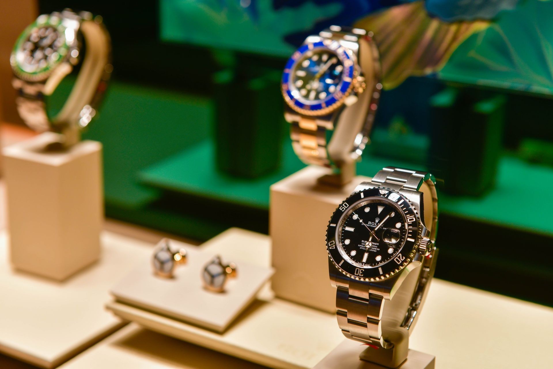 Luxury wristwatches displayed on stands in a jewelry store with green lighting in the background.