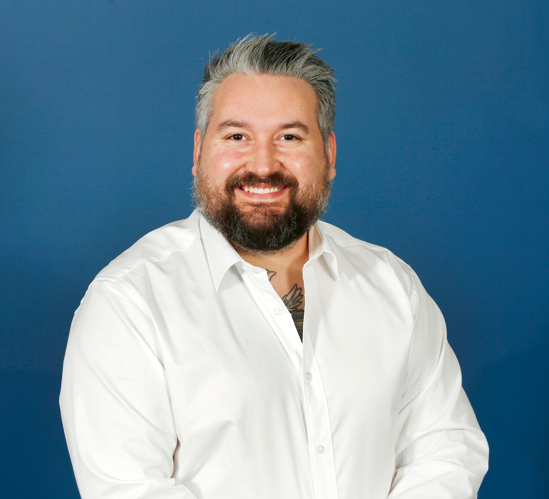 Person in a white shirt standing against a blue background