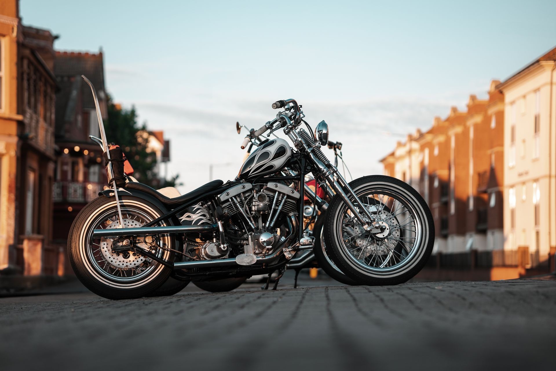 Custom chopper motorcycle parked on a cobblestone street in the evening light.
