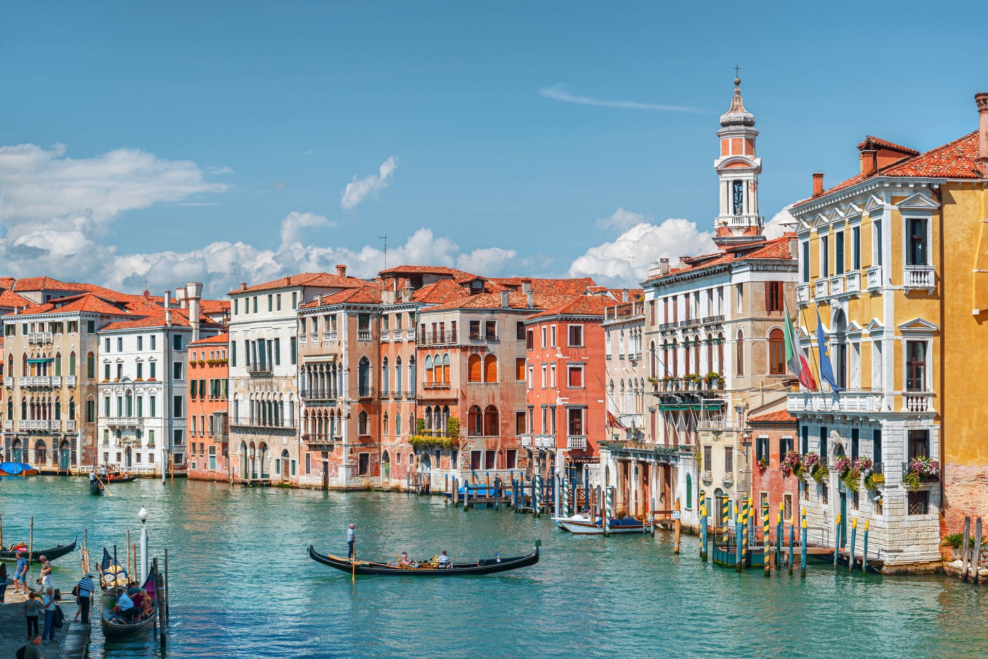 Colorful historic buildings and gondola on a canal in Venice under a clear blue sky.