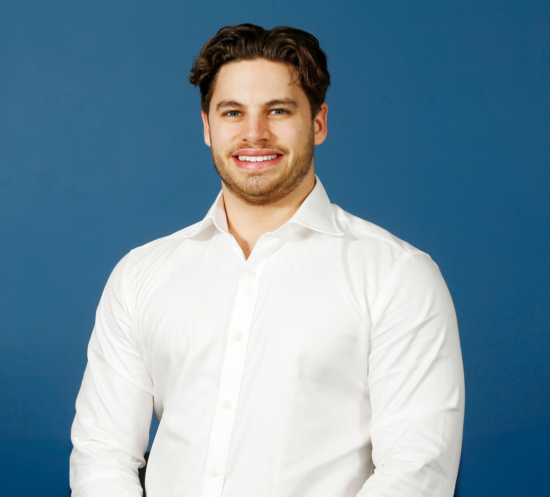 Person in a white shirt standing against a blue background