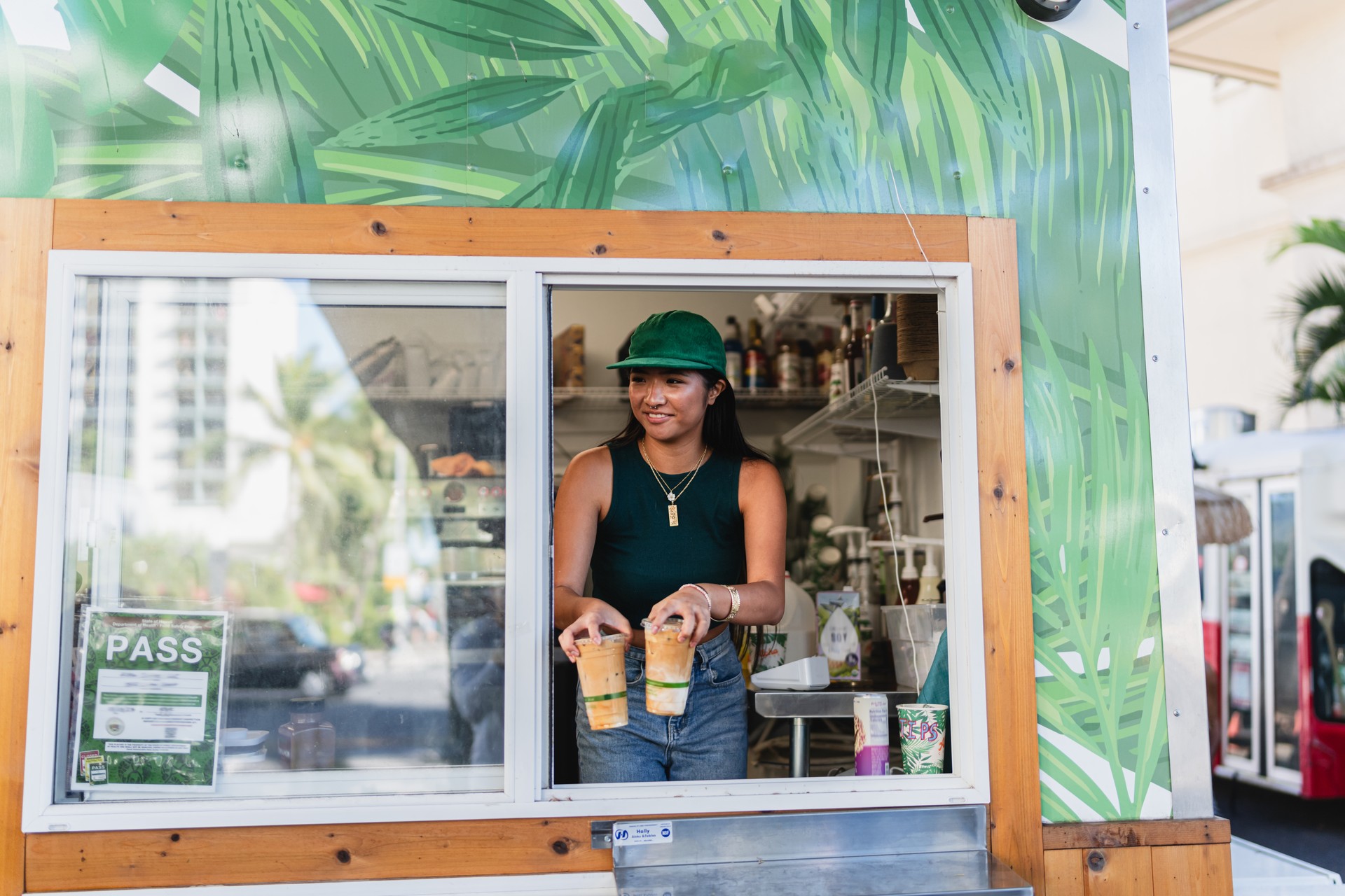 Female barista holds coffee out a food truck window