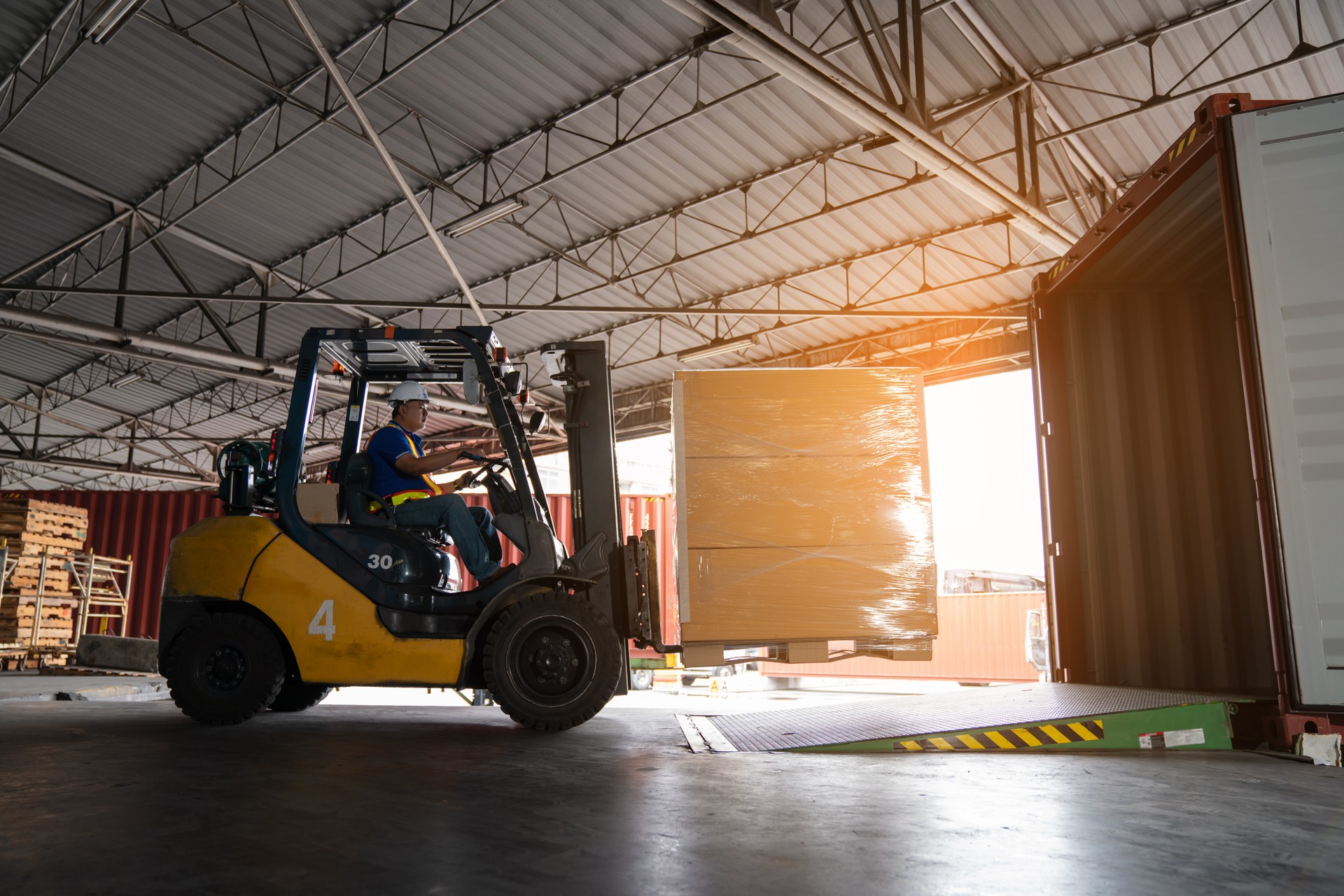 Warehouse worker driver in uniform delivery and loading pallet product.